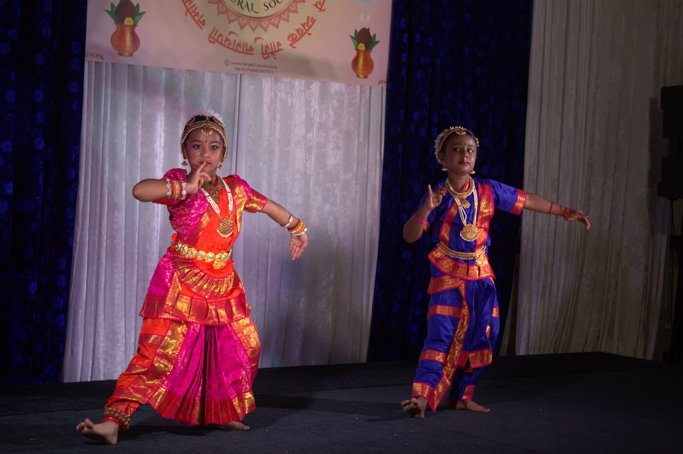 Two young girls performing a dance at TBCS Durga Puja